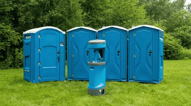 Four blue portable toilets and a matching hand washing station on grass near trees, a common sight at local outdoor events in Shreveport, LA